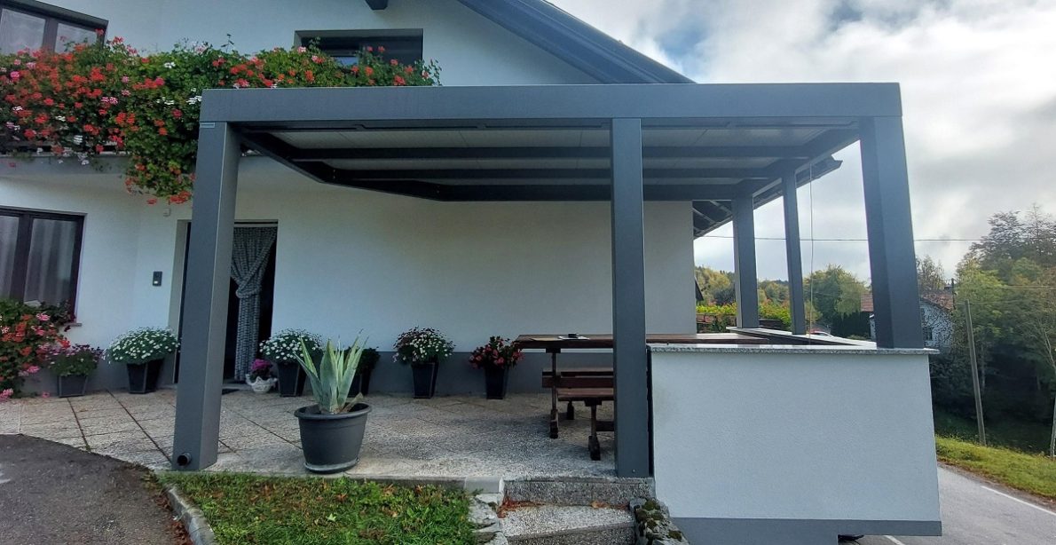 Jekleni nadstrešek ob hiši z ravno streho in nosilnimi stebri