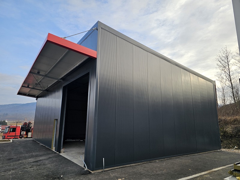 Jeklena konstrukcija industrijske hale z antracit panelnimi ploščami in ravno streho